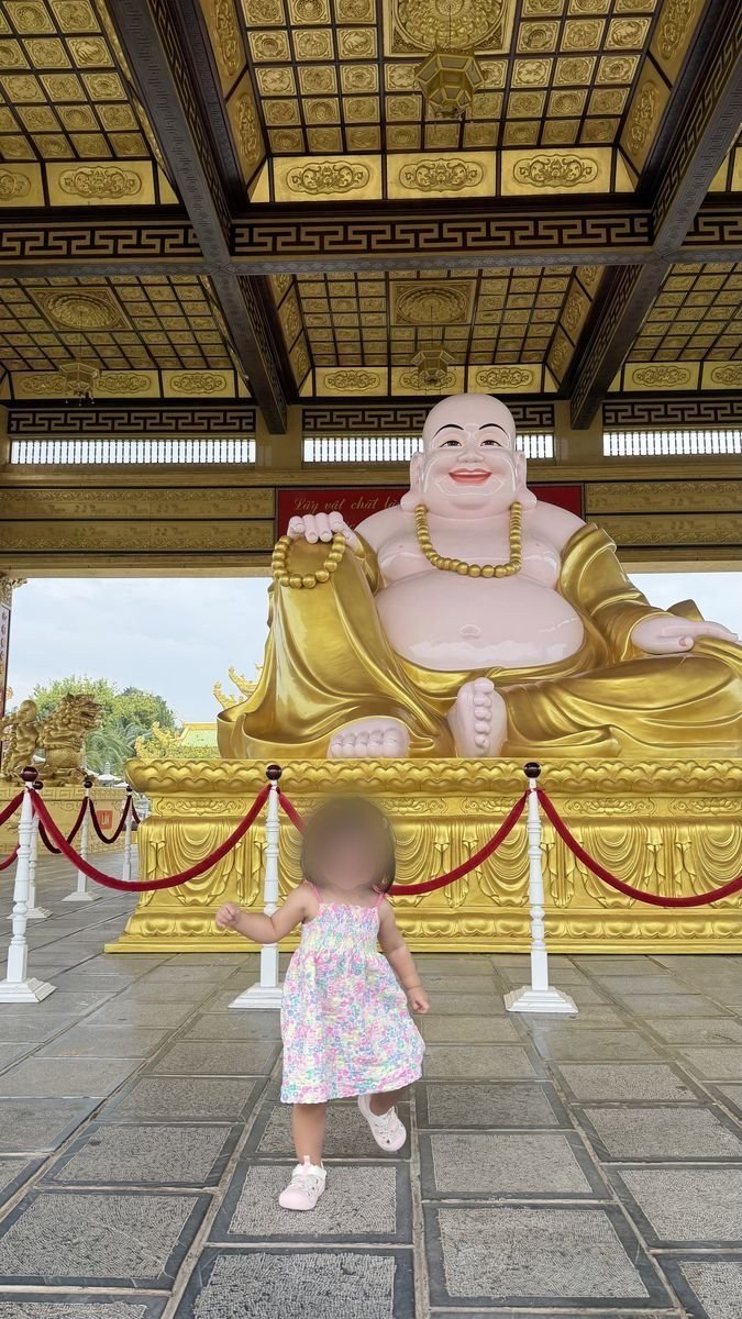 Bé đứng trước tượng Phật Di Lặc tại Đại Nam